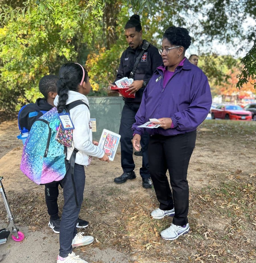 Kim Short handing out safety materials to schoolchildren alongside a Prince William County Fire and Rescue officer